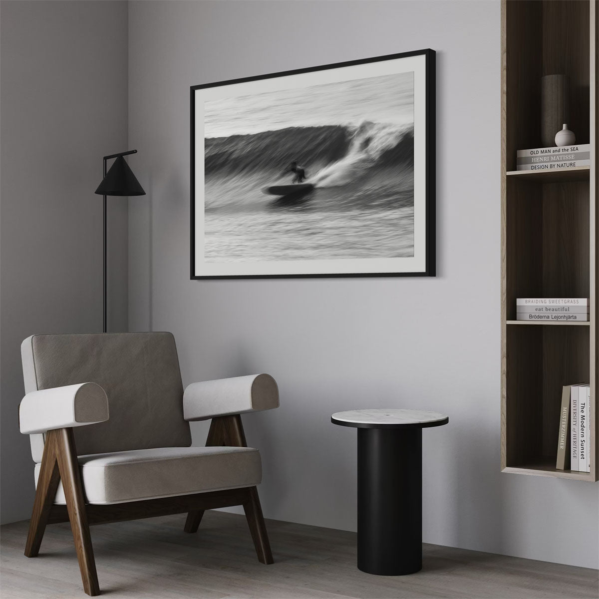 A framed black-and-white photograph of a surfer surfing a wave. The wall art hangs on a wall in a modern-themed entryway.
