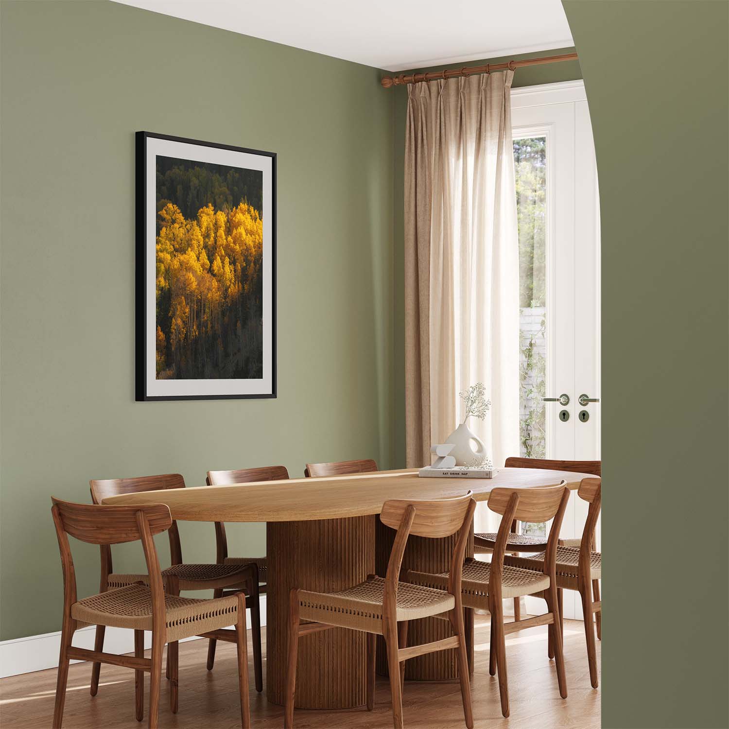 A framed photograph of yellow aspen trees during autumn season hangs on a green wall in a modern dining room.