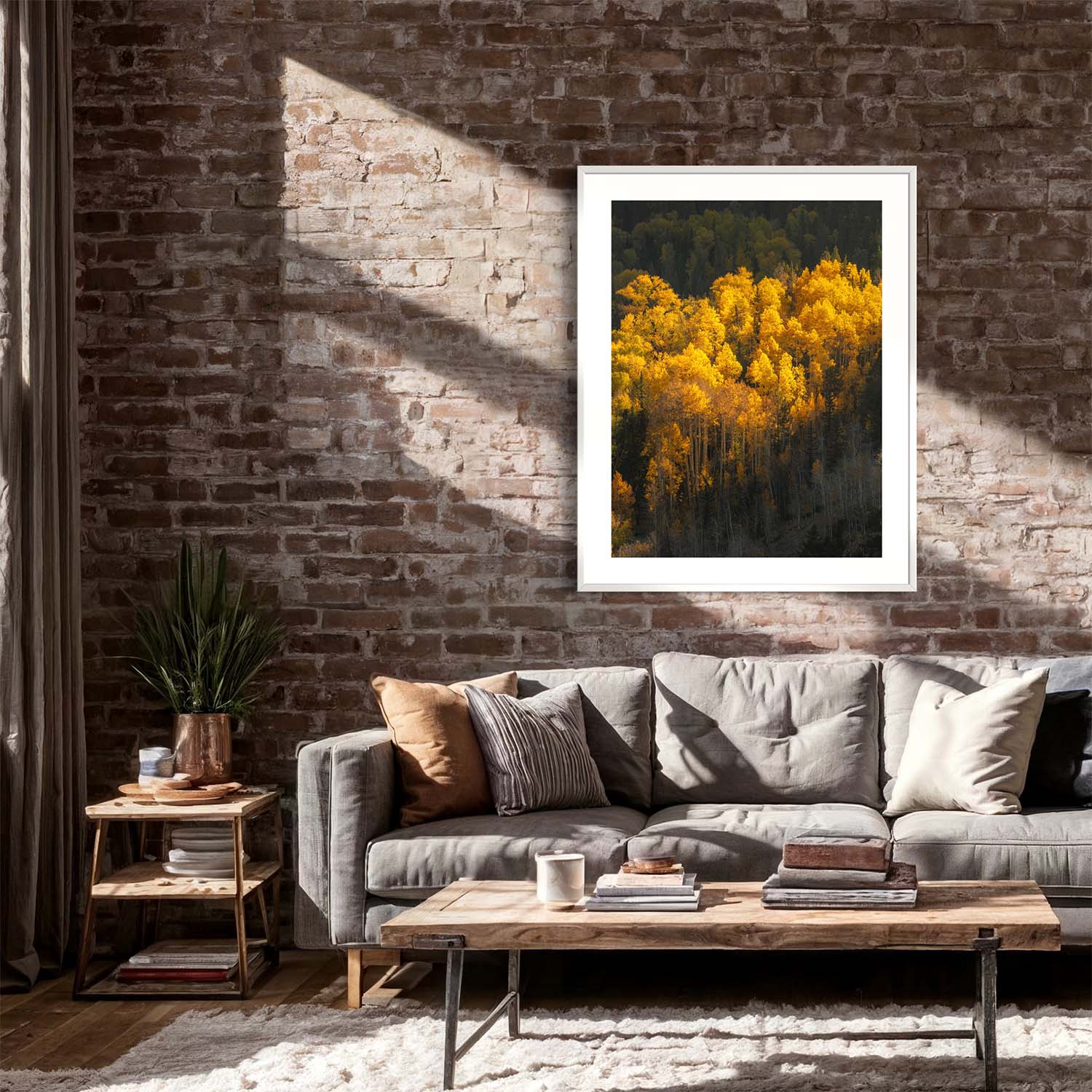 A framed photograph of yellow aspen trees during autumn season hangs on a brick wall in a rustic living room.