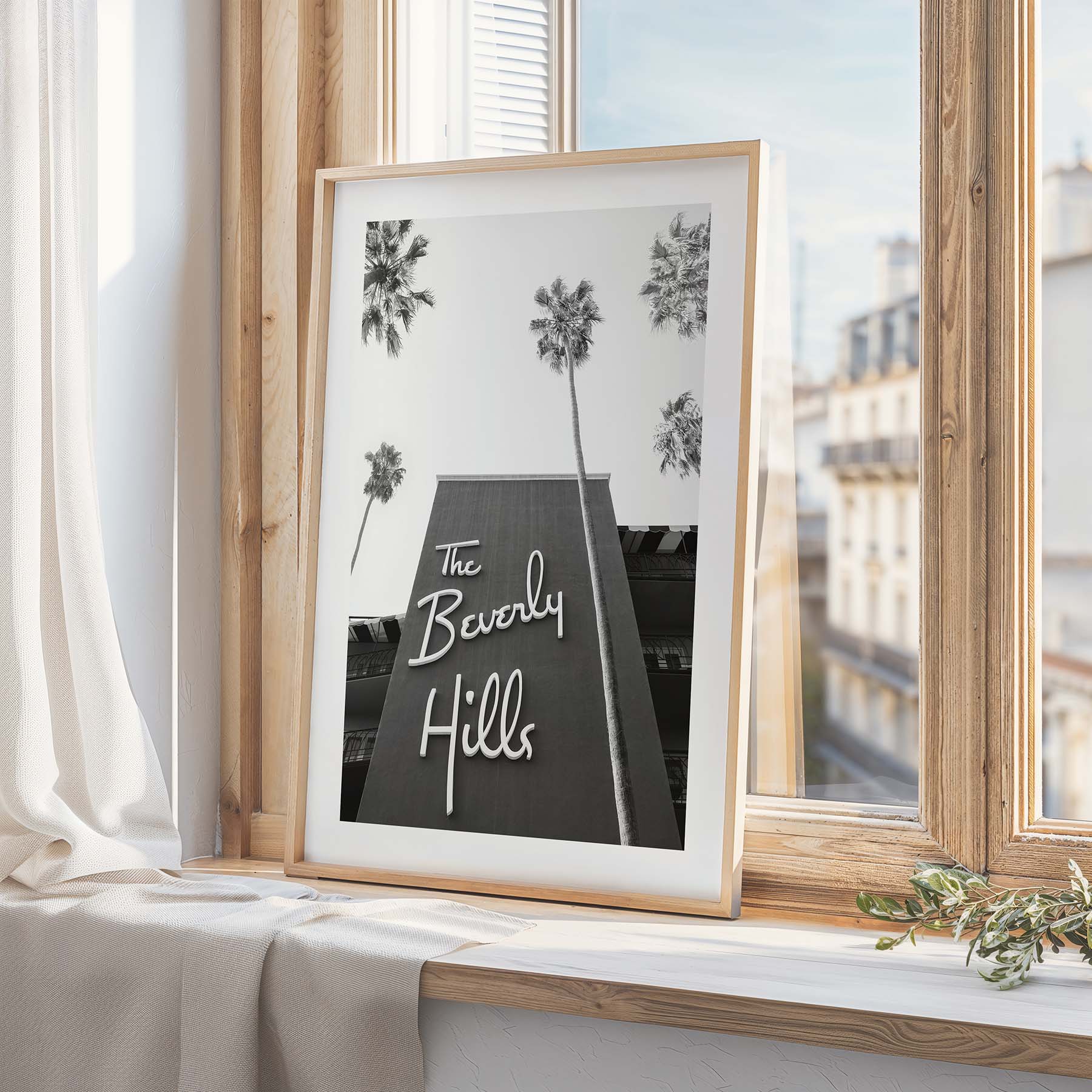 A framed black and white photograph of the Beverly Hills Hotel sits on the ledge of a window in a modern-themed home.