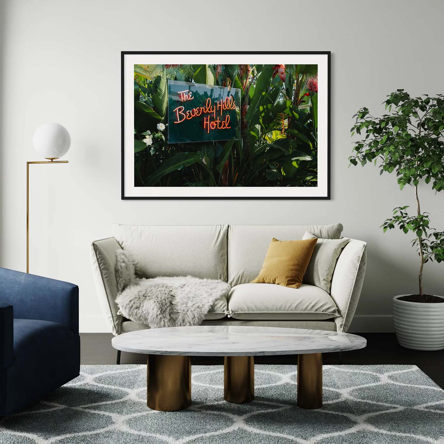 A fine art photography print of the neon sign from the entrance to the Beverly Hills Hotel hangs above a couch in a mid-century modern living room.