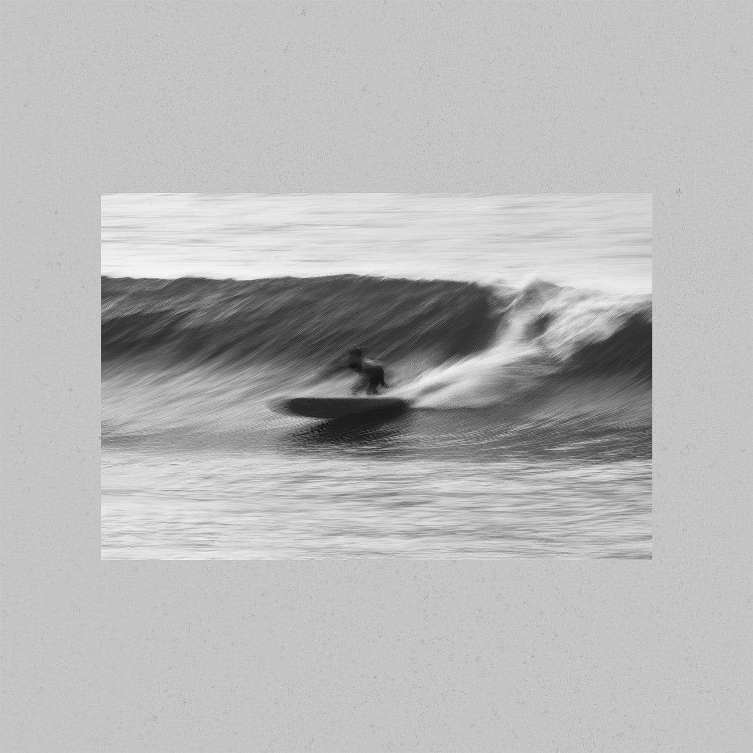 A black-and-white photograph of a surfer surfing a wave.