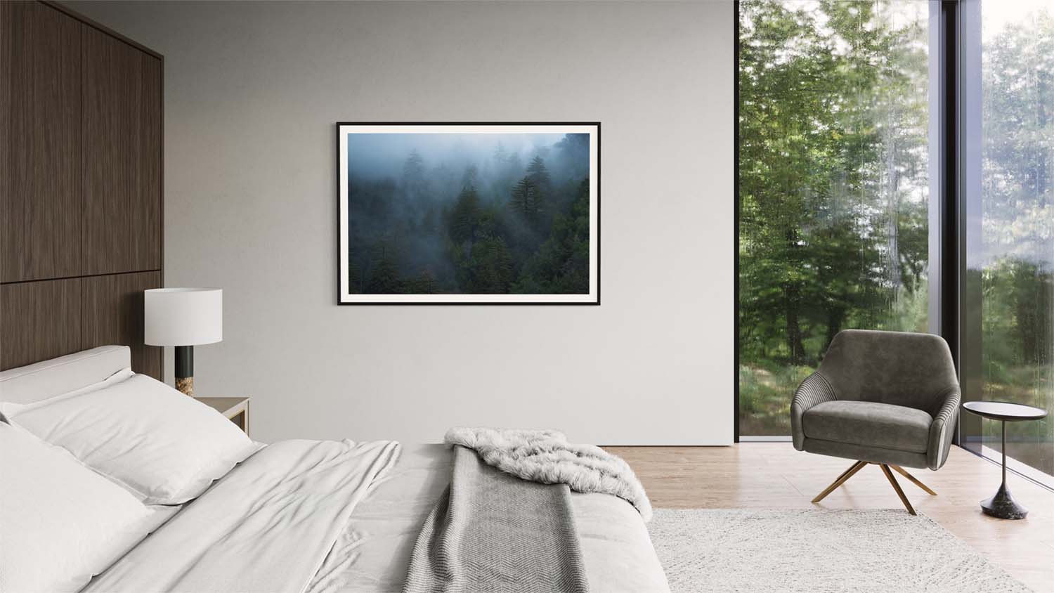 A framed photograph of foggy forest trees hangs on a wall in a modern bedroom.