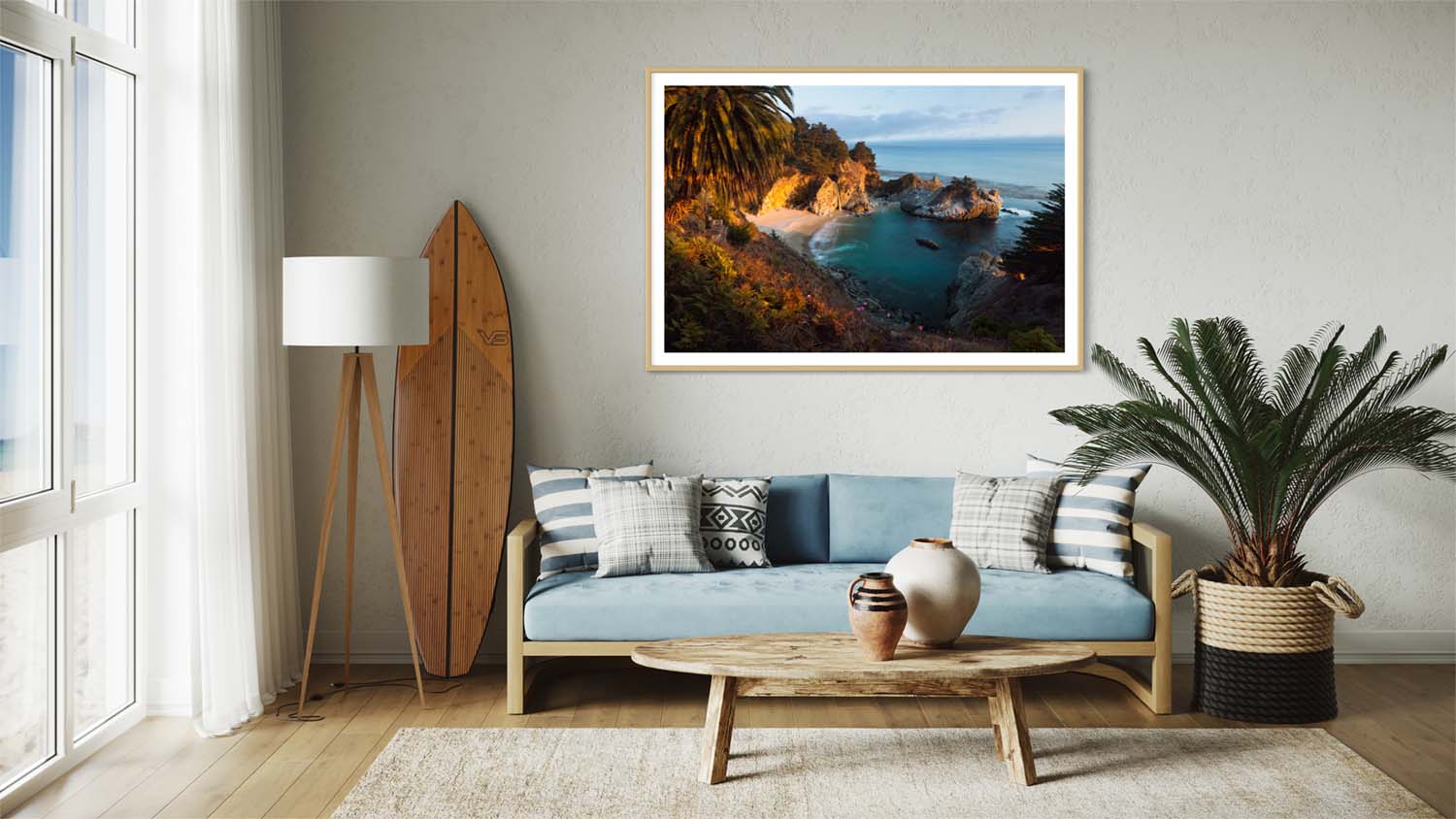 A framed fine art photograph of McWay Falls hangs on a wall above a couch in a mid-century modern styled living room.
