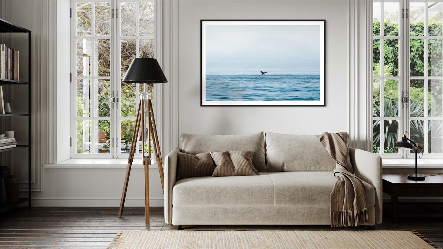 A framed fine art photograph of a breaching whale hangs on a wall above a couch in a mid-century modern styled living room.