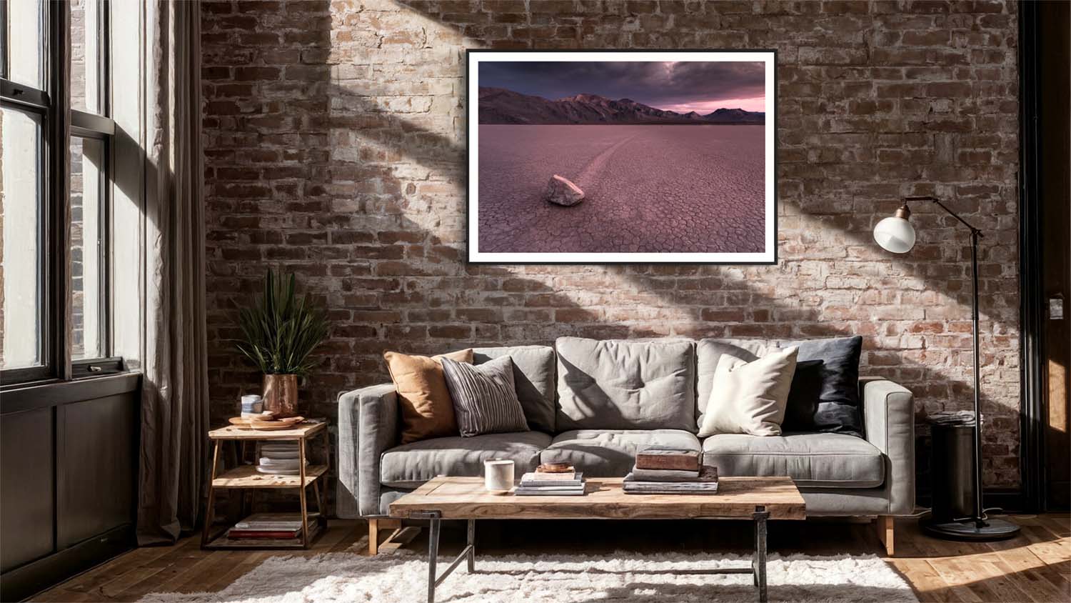 A framed fine art photograph of a sliding rock at Death Valley hangs on a wall above a couch in a mid-century modern styled living room.