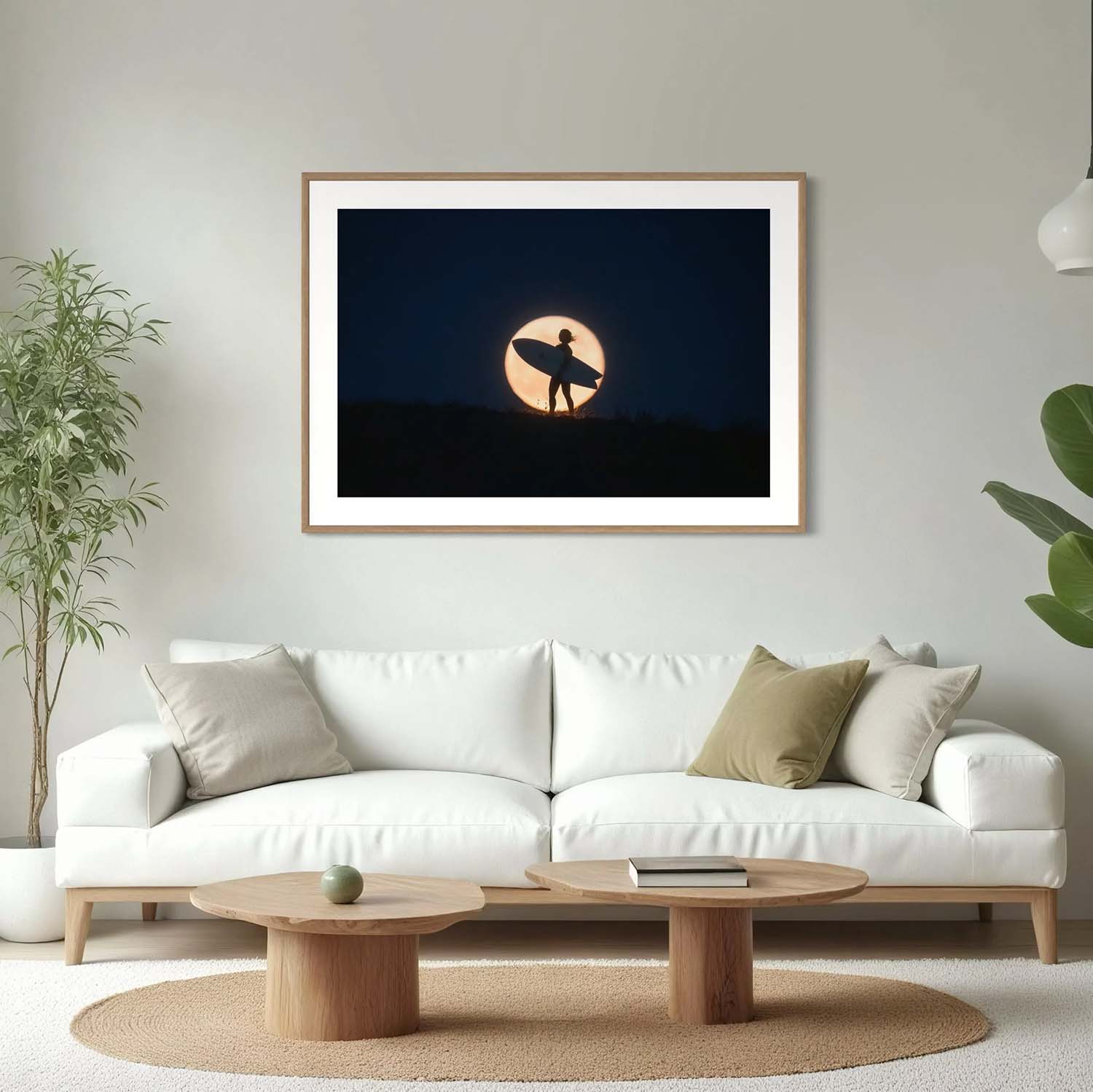 A photography print of a surfer standing against the backdrop of a full moon hanging in a mid-century modern living room.
