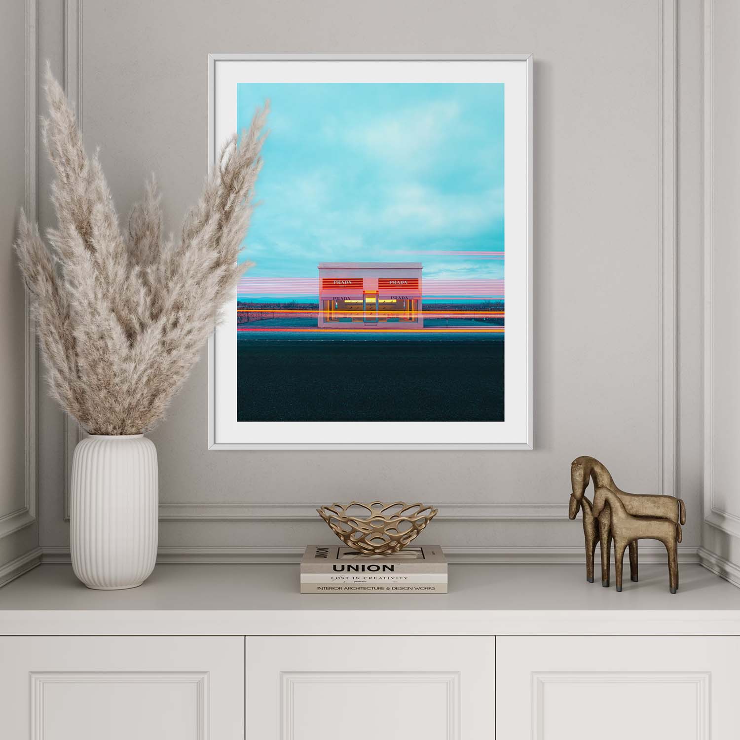 A framed photograph of the Prada Marfa art installation hanging on the wall in a modern entryway.