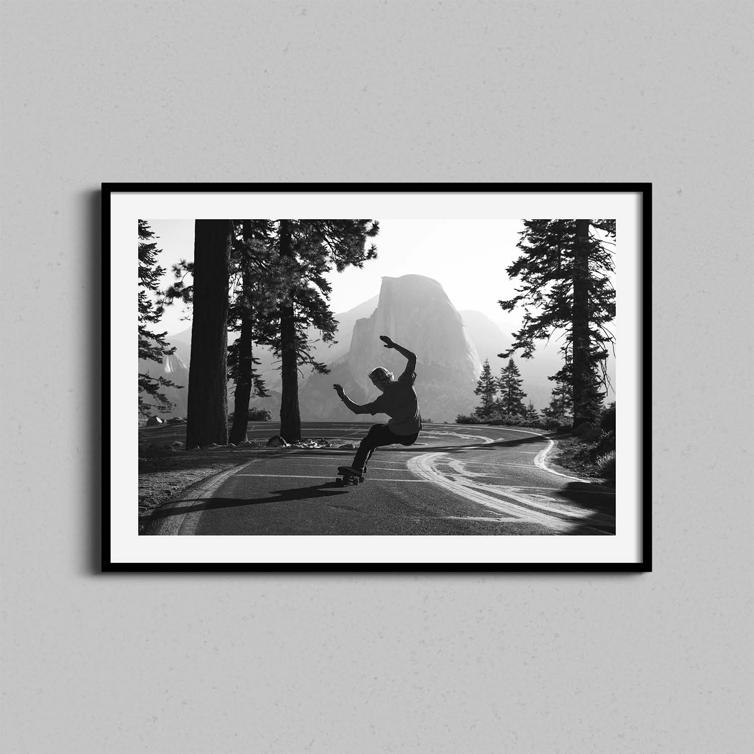 A black and white photograph of a skateboarder in Yosemite National Park framed in a black wooden frame.