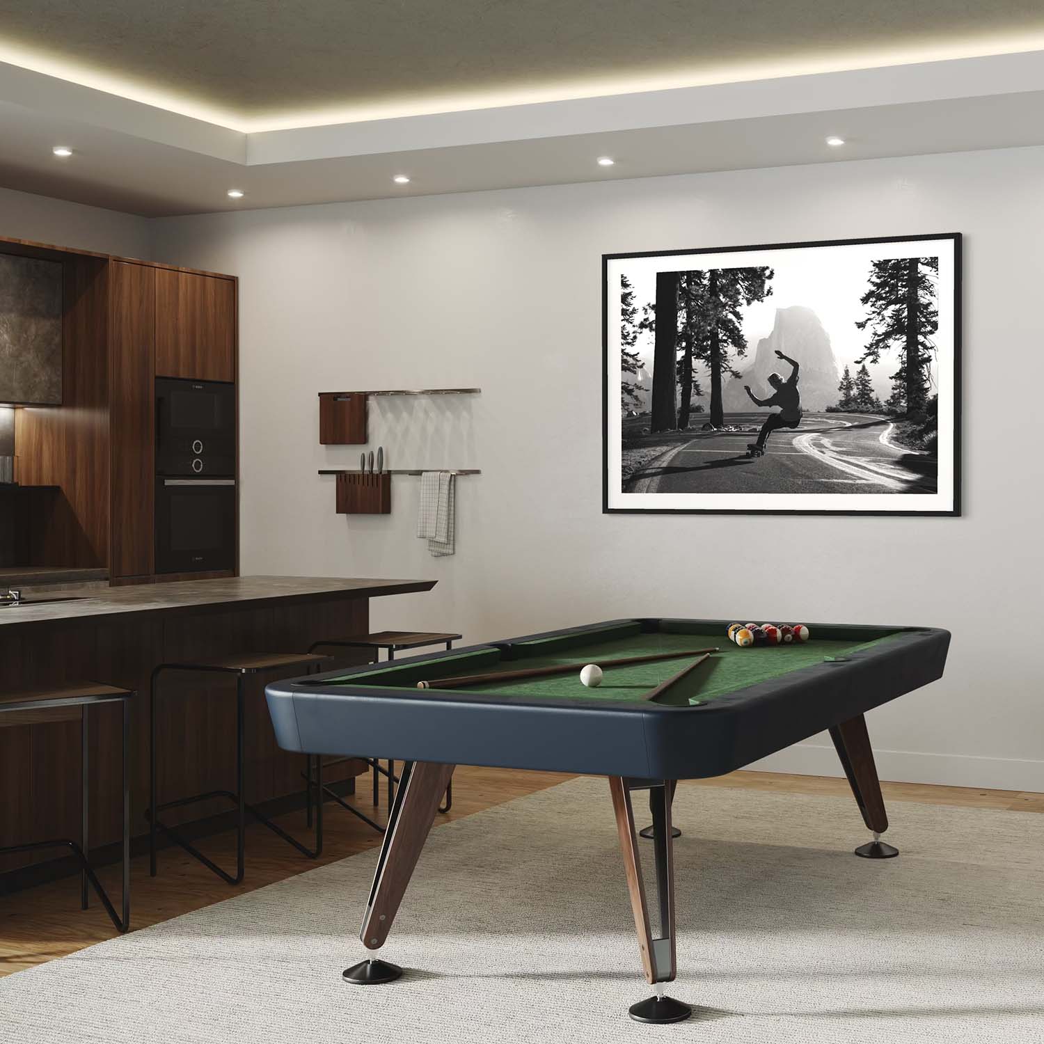 A framed photograph of a skateboarder in Yosemite National Park hangs on a wall above a pool table.