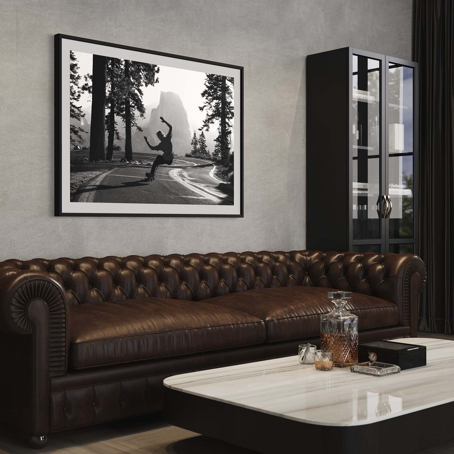 A framed photograph of a skateboarder in Yosemite National Park hangs on a wall above a couch in a contemporary living room.