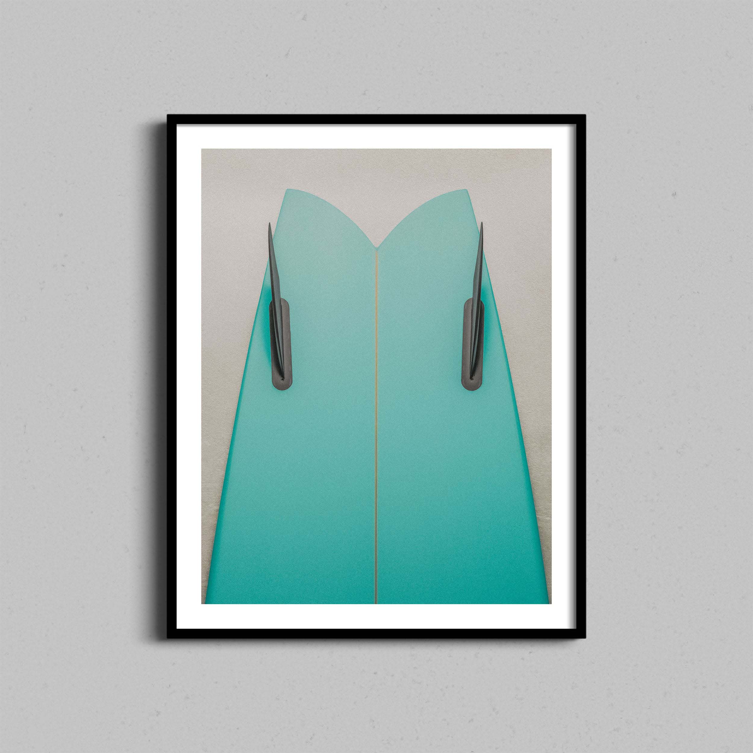 Fine art photography print featuring a green surfboard leaning against a cream textured wall framed with a black wooden frame.