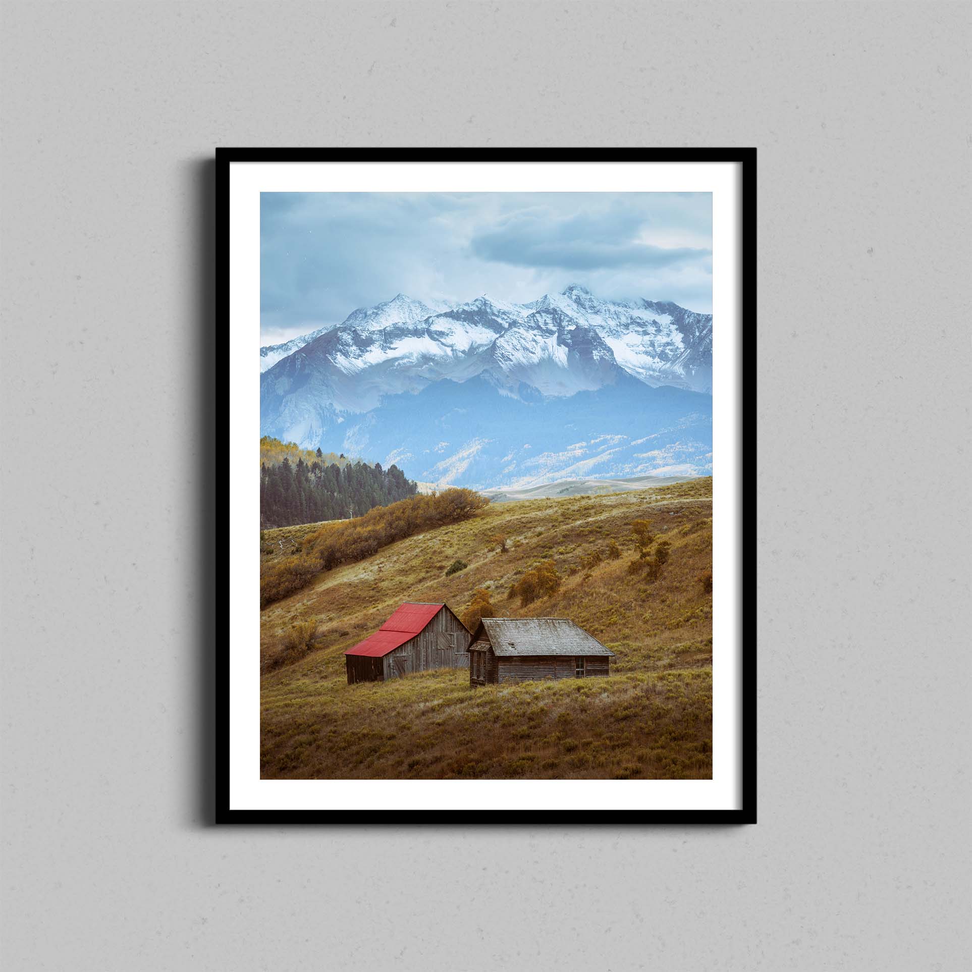 A photograph of barns outside of Telluride, Colorado hangs on a wall in a black wooden frame.