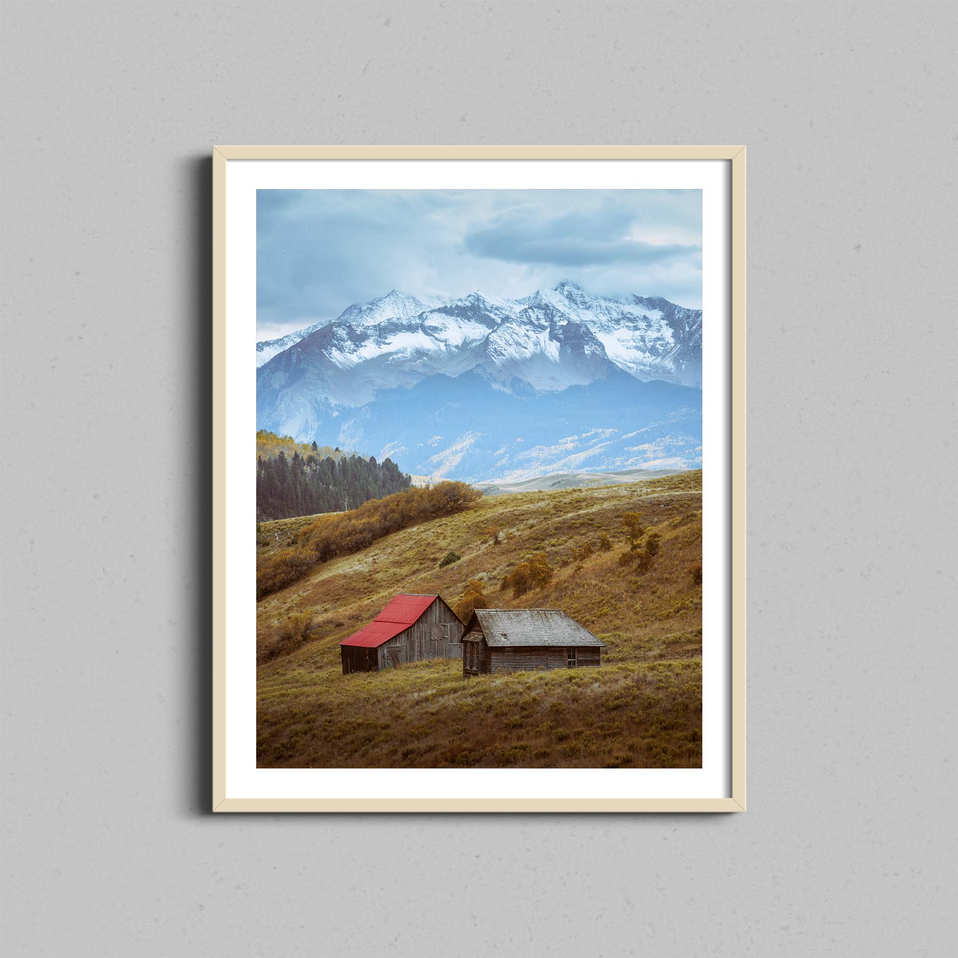 A photograph of barns outside of Telluride, Colorado hangs on a wall in a natural wooden frame.