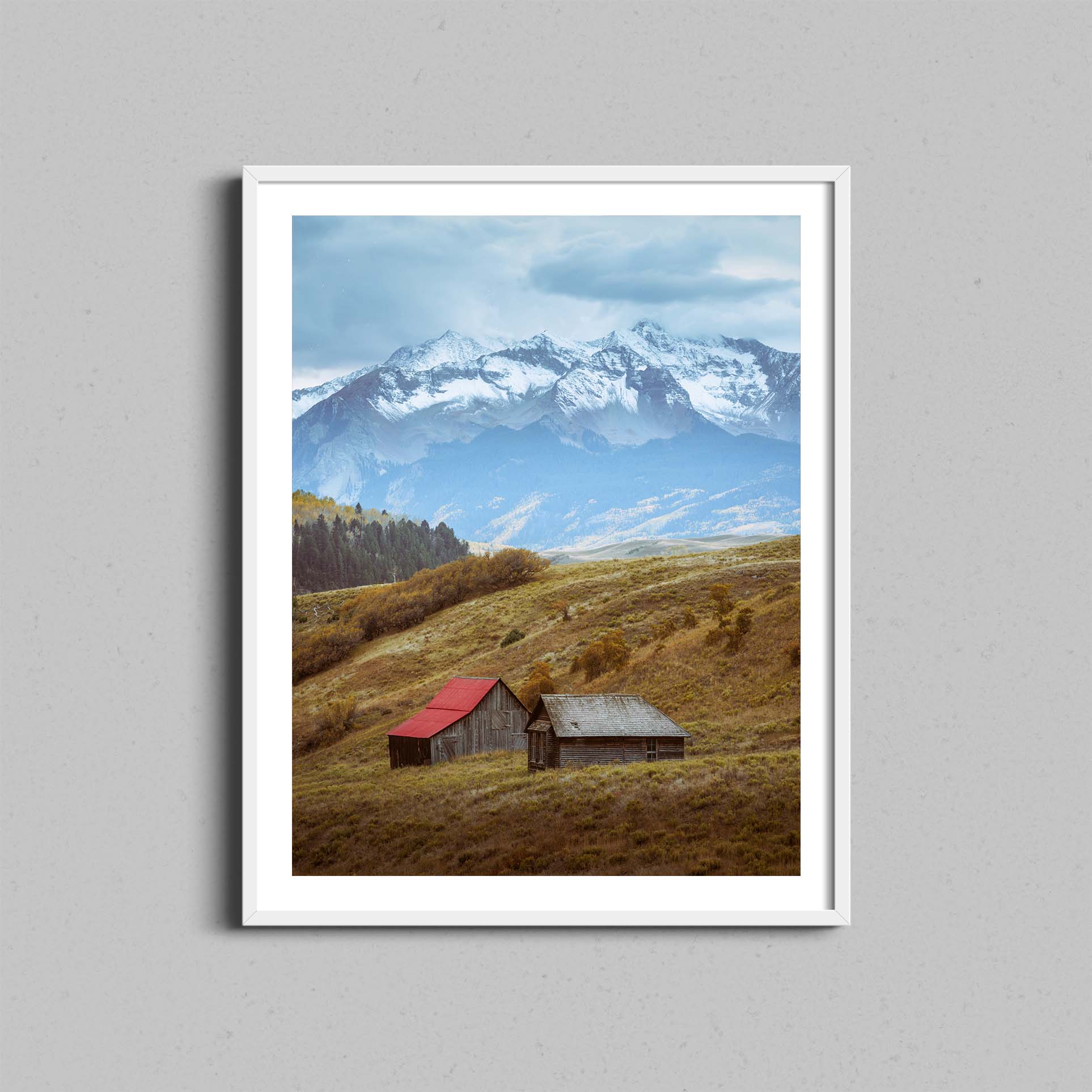 A photograph of barns outside of Telluride, Colorado hangs on a wall in a white wooden frame.