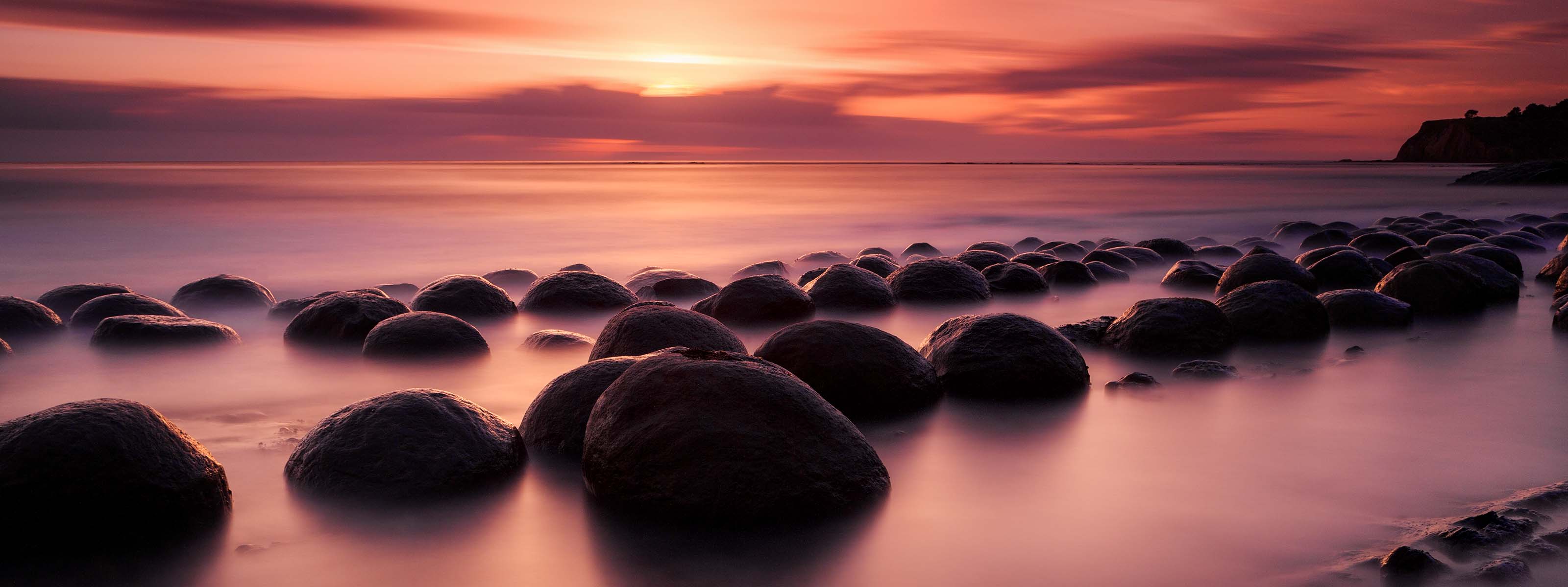 A vibrant sunset over rocks on a beach in Northern California. 