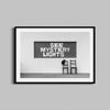 A black and white photography print of the See Mystery Lights sign in Marfa, Texas with a black wooden frame.