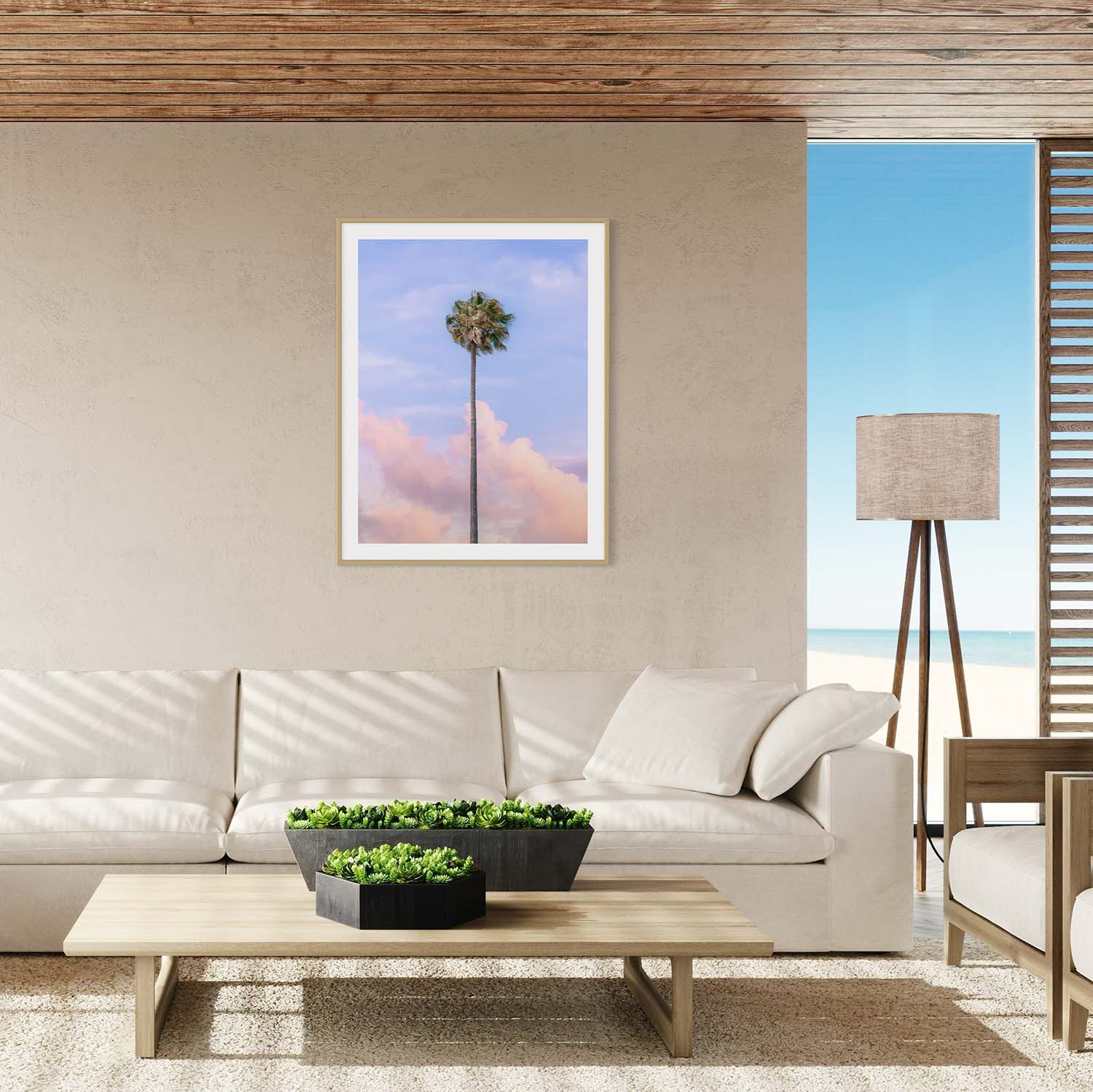 A framed photograph of a single palm tree against a sunset sky hanging on a wall in a coastal-themed living room.