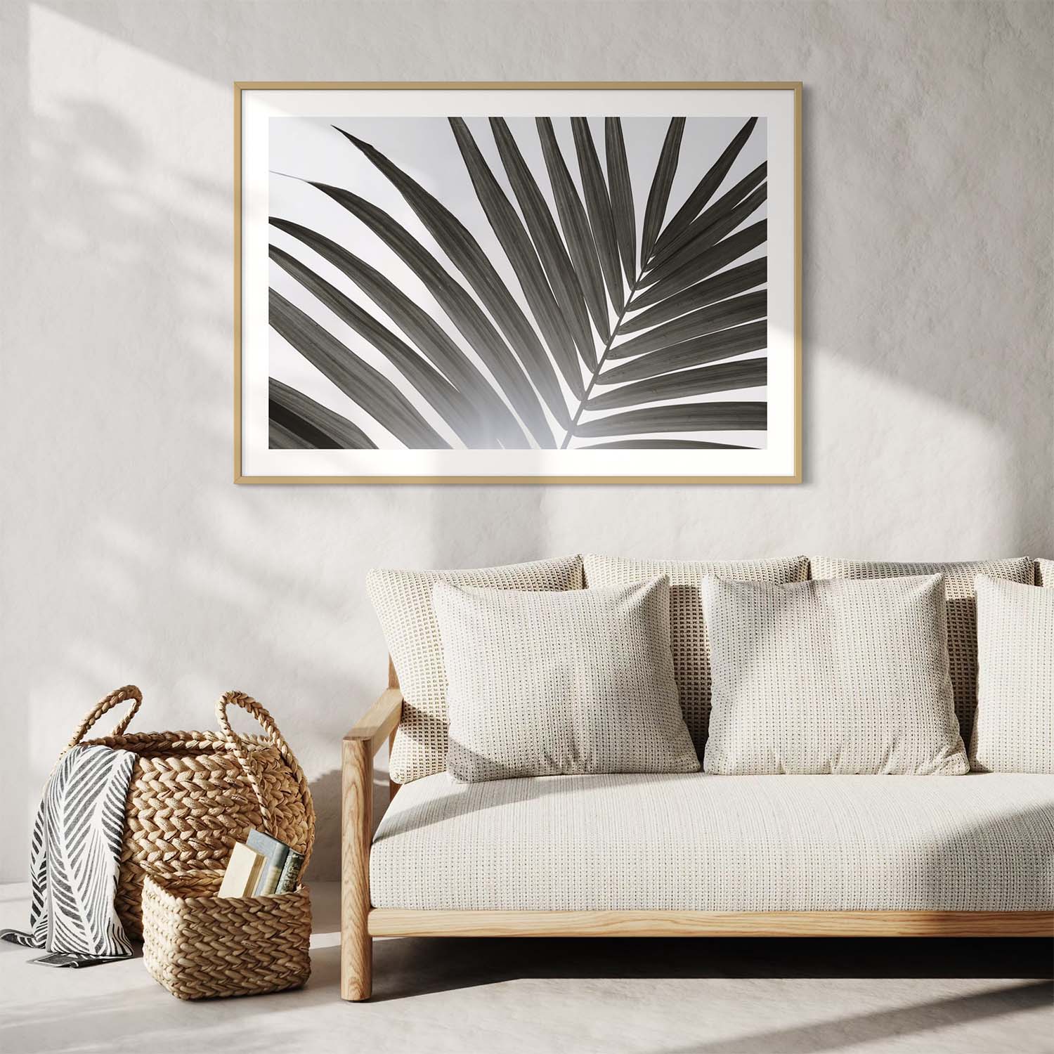 A framed black and white photograph of a palm tree leaf hangs on a wall over a couch in a contemporary entryway.