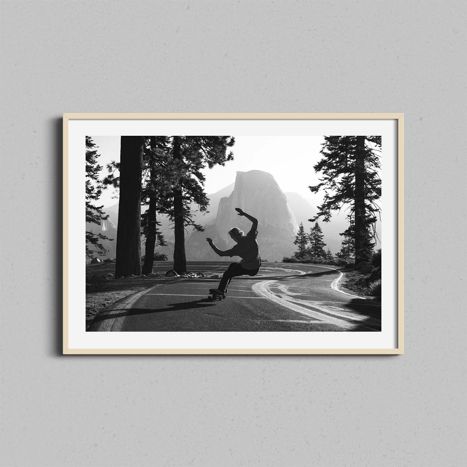 A black and white photograph of a skateboarder in Yosemite National Park framed in a natural wooden frame.