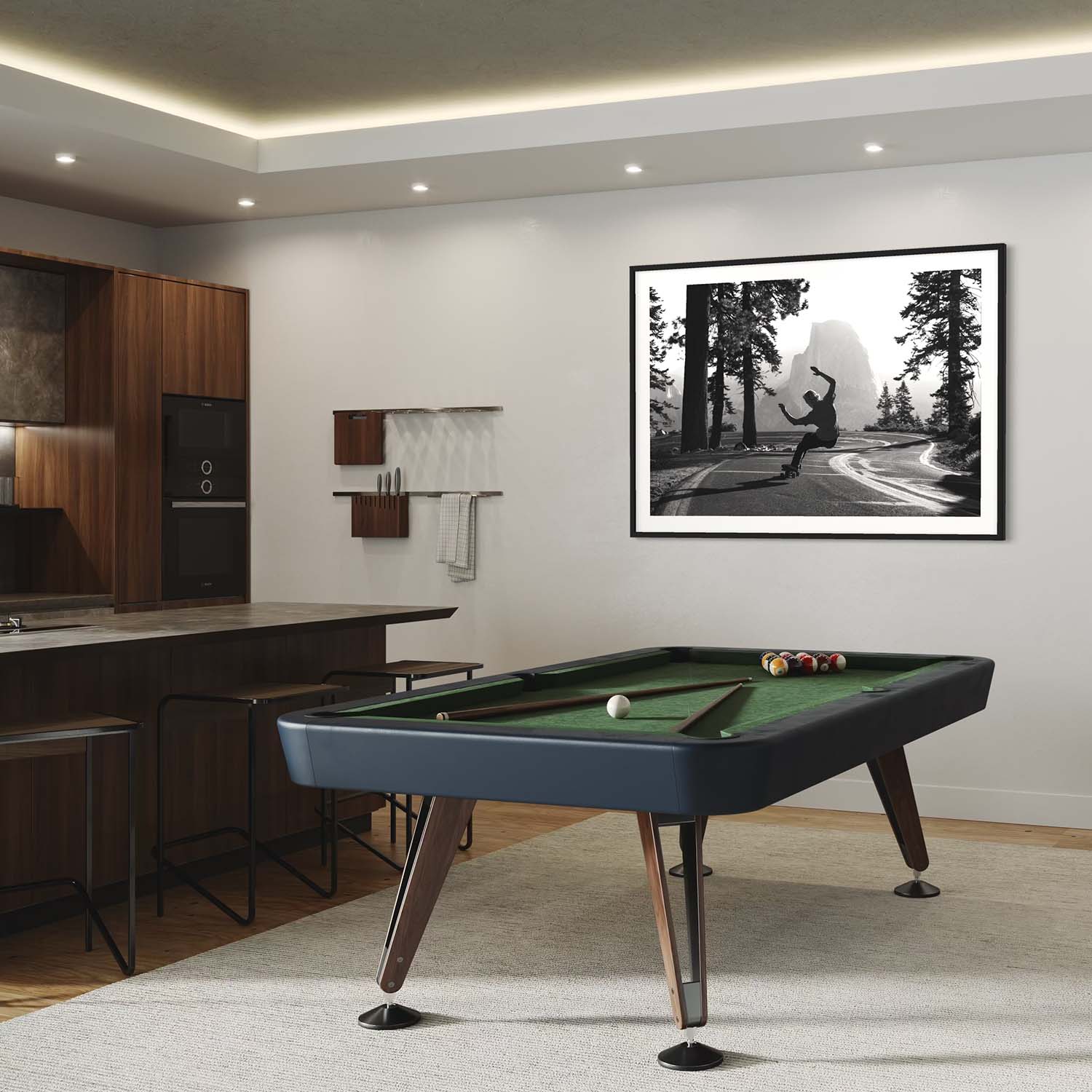 A framed photograph of a skateboarder in Yosemite National Park hangs on a wall above a pool table. 