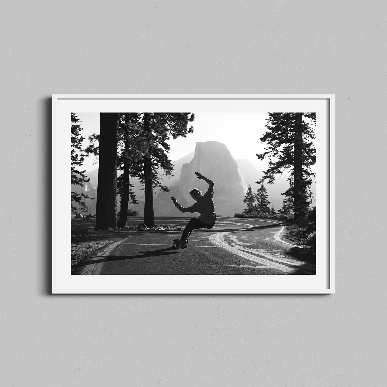 A black and white photograph of a skateboarder in Yosemite National Park framed in a white wooden frame.